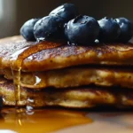 Golden-brown Premier Protein pancakes with fresh berries and syrup.