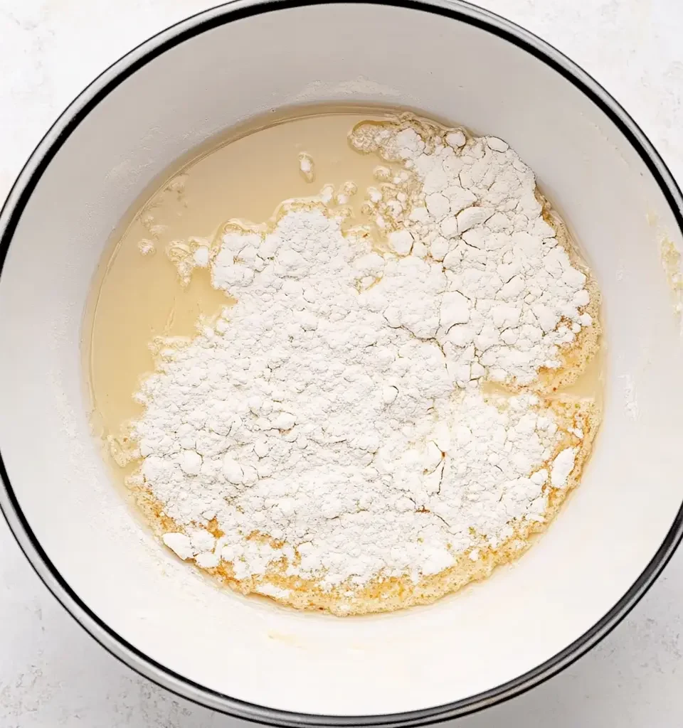 The Best Pancake Muffin Recipe: Easy, Fluffy, and Delicious 11 Flour is being added to a wet mixture in a bowl, beginning the process of forming a smooth pancake muffin batter.