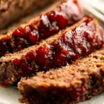 Juicy sliced meatloaf with a caramelized BBQ glaze on a white plate