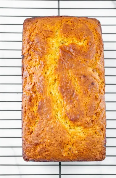 Easy & Delicious Banana Bread Recipe with Cake Mix 16 A banana bread loaf cooling on a wire rack, showing a crisp, golden crust.